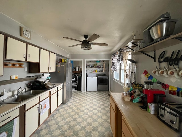 kitchen with light floors, light countertops, freestanding refrigerator, white cabinetry, and a sink