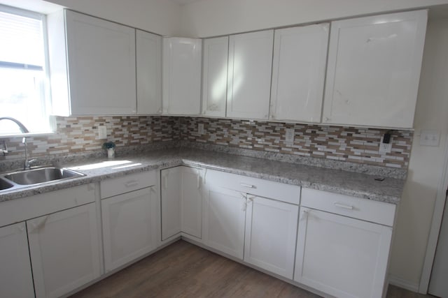 kitchen with wood finished floors, tasteful backsplash, a sink, and white cabinetry