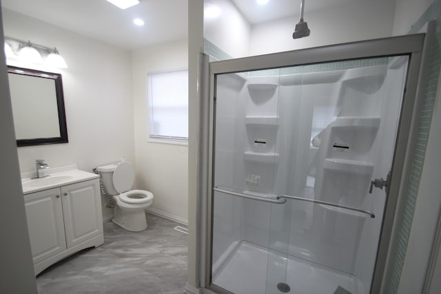 bathroom featuring toilet, a stall shower, vanity, and baseboards