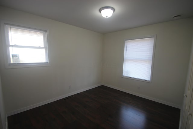 unfurnished room with dark wood finished floors and baseboards