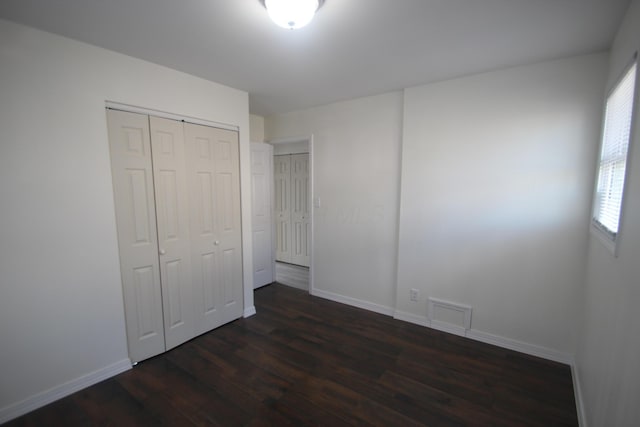 unfurnished bedroom featuring dark wood-style floors, a closet, and baseboards