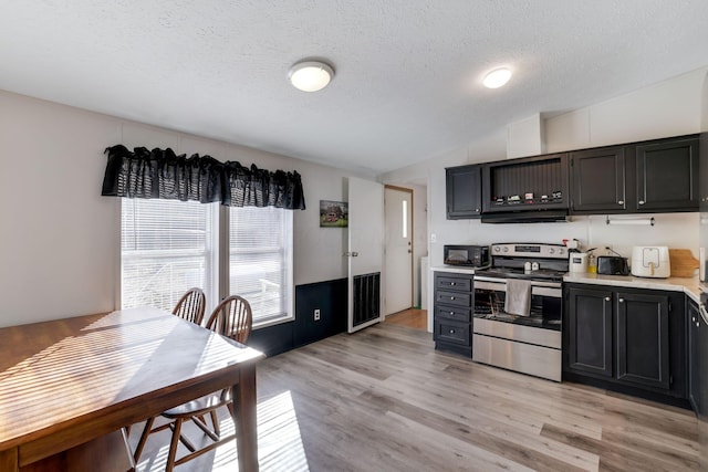 kitchen featuring black microwave, light countertops, dark cabinetry, light wood-style floors, and electric range