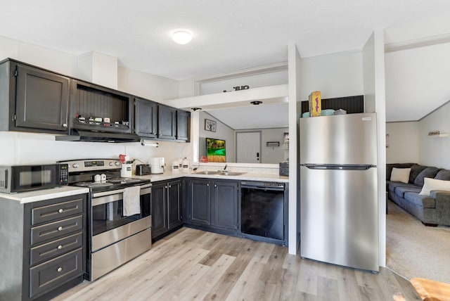 kitchen featuring light wood finished floors, extractor fan, light countertops, black appliances, and a sink