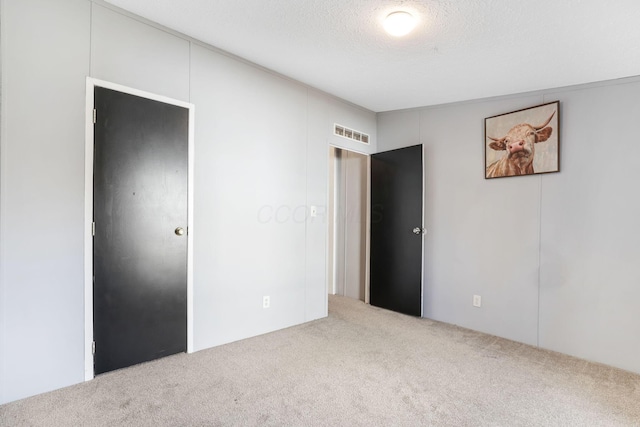 unfurnished bedroom featuring visible vents, carpet floors, and a textured ceiling