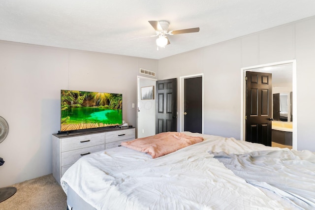 bedroom featuring ceiling fan, visible vents, carpet floors, and ensuite bath