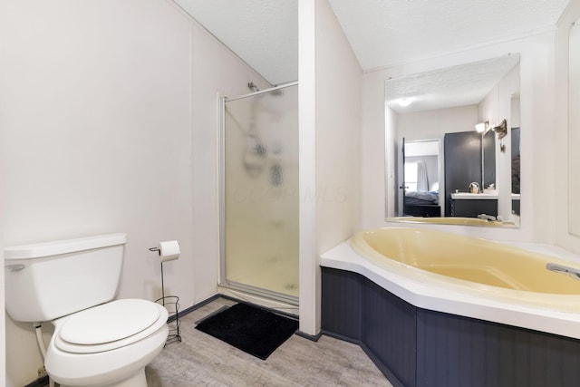 full bath with toilet, a stall shower, ensuite bathroom, wood finished floors, and a textured ceiling