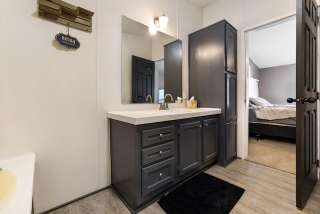 ensuite bathroom with vanity, wood finished floors, and ensuite bathroom