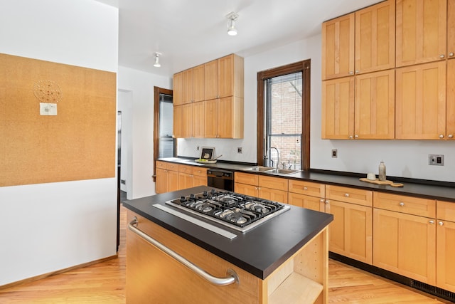 kitchen with stainless steel gas cooktop, light wood finished floors, dark countertops, a sink, and dishwasher