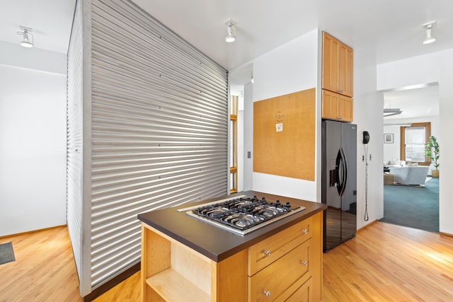 kitchen featuring light wood-style flooring, black fridge, open shelves, dark countertops, and stainless steel gas stovetop