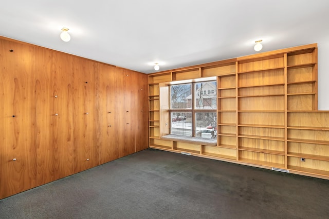 empty room with wood walls and dark carpet