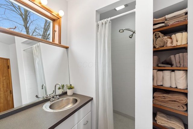 bathroom with tiled shower and vanity