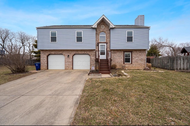 raised ranch featuring concrete driveway, brick siding, a front lawn, and fence