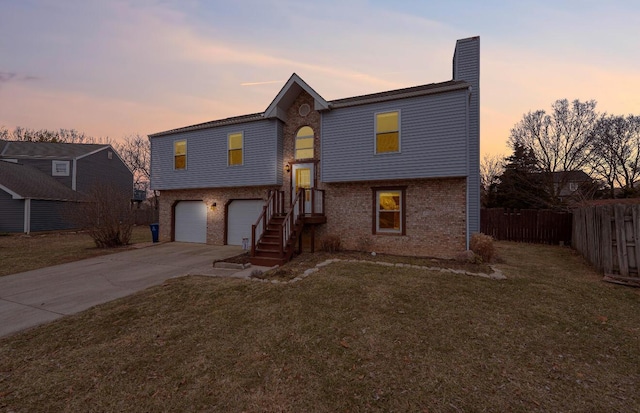 split foyer home featuring driveway, an attached garage, fence, and brick siding