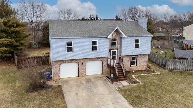 raised ranch with driveway, a chimney, fence, and a front lawn