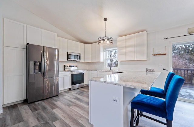 kitchen with pendant lighting, a breakfast bar area, stainless steel appliances, white cabinets, and a peninsula