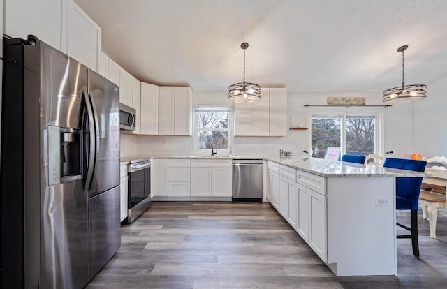 kitchen featuring a breakfast bar, pendant lighting, stainless steel appliances, and white cabinets