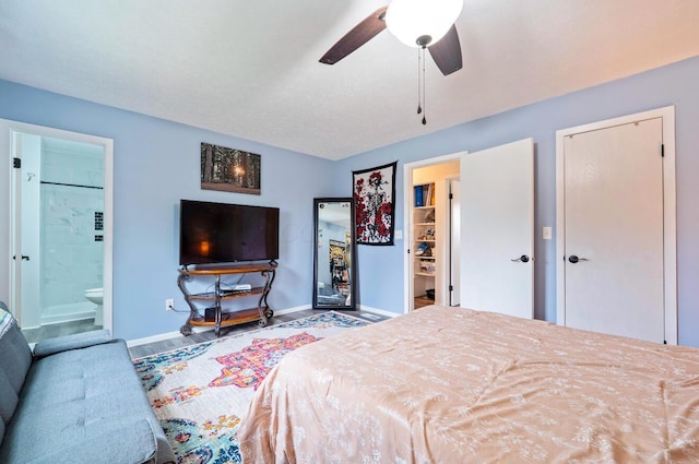 bedroom with a ceiling fan, baseboards, wood finished floors, and ensuite bathroom