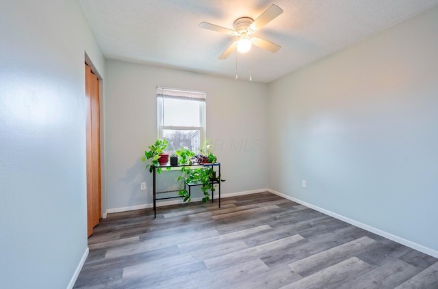 spare room featuring ceiling fan, a textured ceiling, wood finished floors, and baseboards