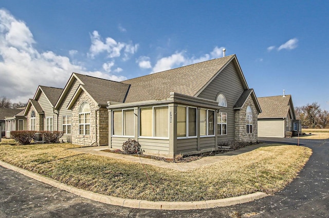 view of property exterior with stone siding and a shingled roof