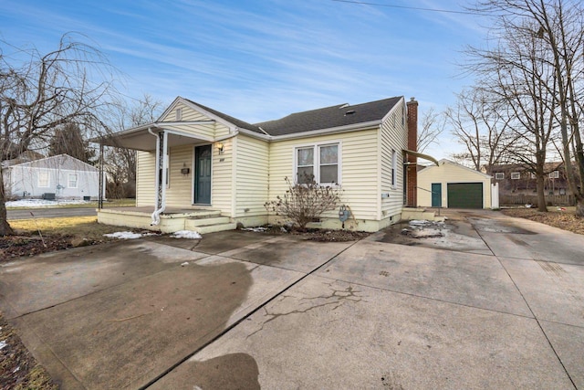 bungalow featuring a garage, a chimney, and an outbuilding