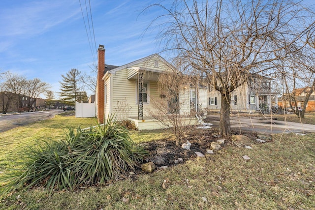 view of front of home featuring fence, a chimney, and a front lawn