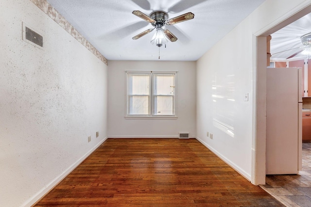 unfurnished room featuring dark wood-style floors, ceiling fan, and visible vents