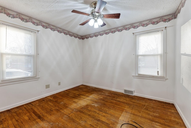 unfurnished room with visible vents, dark wood-type flooring, ceiling fan, a textured ceiling, and baseboards