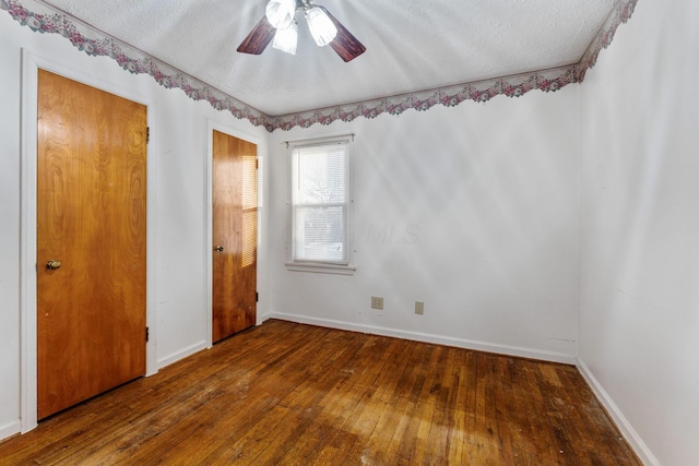 spare room with baseboards, dark wood finished floors, and a textured ceiling