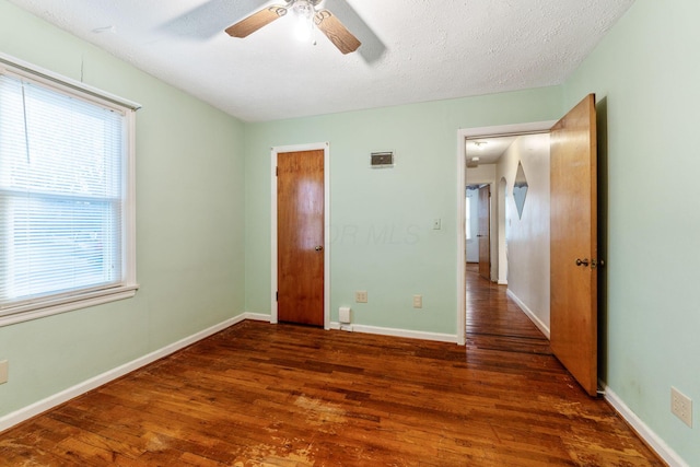 unfurnished bedroom with a textured ceiling, dark wood-type flooring, a ceiling fan, and baseboards