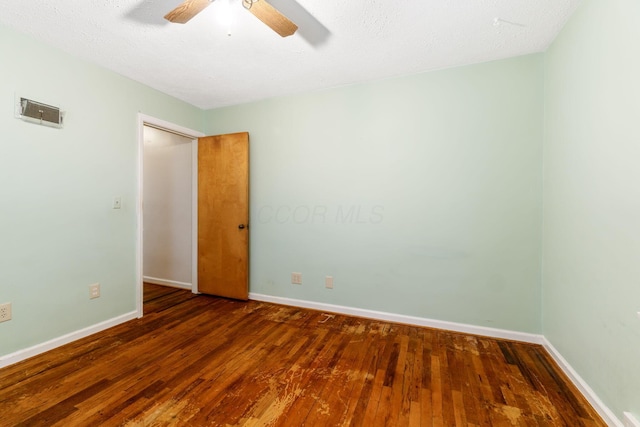 spare room featuring a ceiling fan, dark wood finished floors, and baseboards