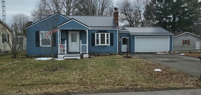 view of front of property with a chimney, a front yard, metal roof, a garage, and driveway