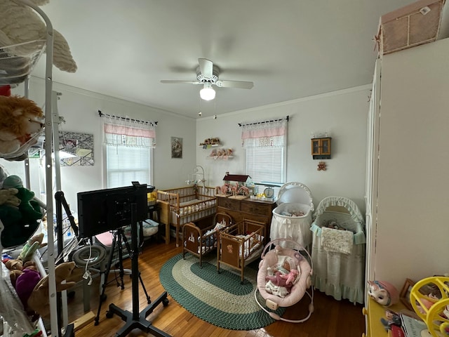 interior space with ornamental molding, a ceiling fan, and wood finished floors