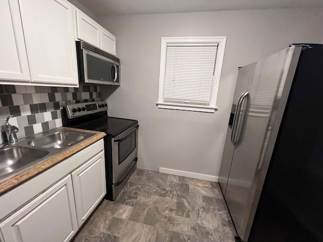 kitchen with a sink, stainless steel appliances, white cabinets, decorative backsplash, and baseboards