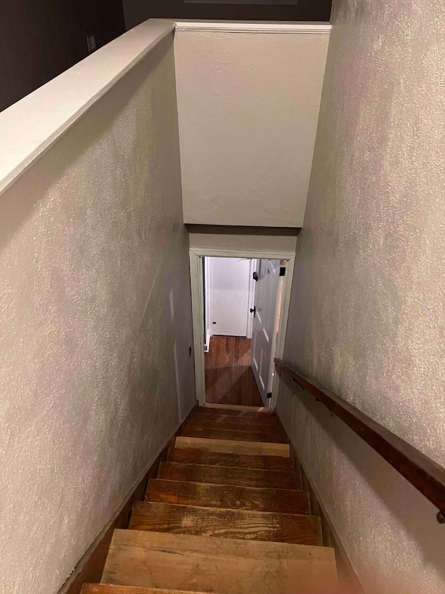 stairway featuring a textured wall and wood-type flooring