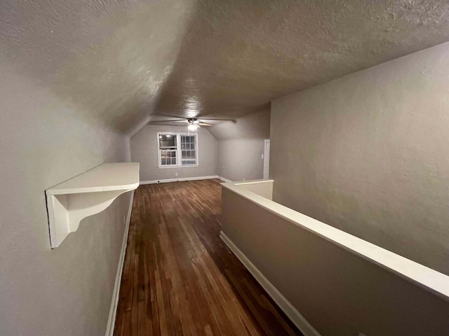 bonus room featuring baseboards, lofted ceiling, a textured ceiling, and dark wood-style flooring