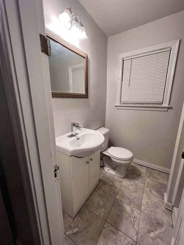 bathroom with baseboards, toilet, and vanity