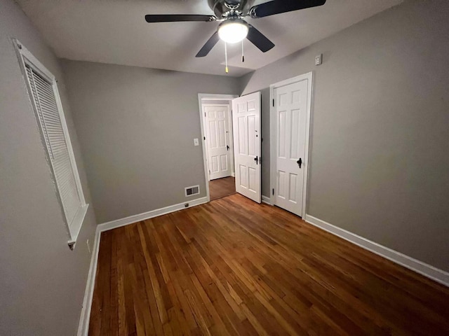 unfurnished bedroom featuring a ceiling fan, wood finished floors, visible vents, and baseboards