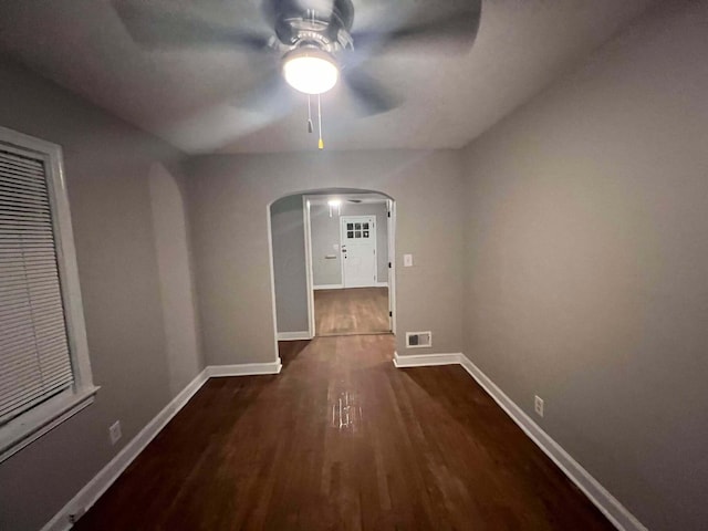 corridor featuring arched walkways, visible vents, baseboards, and wood finished floors