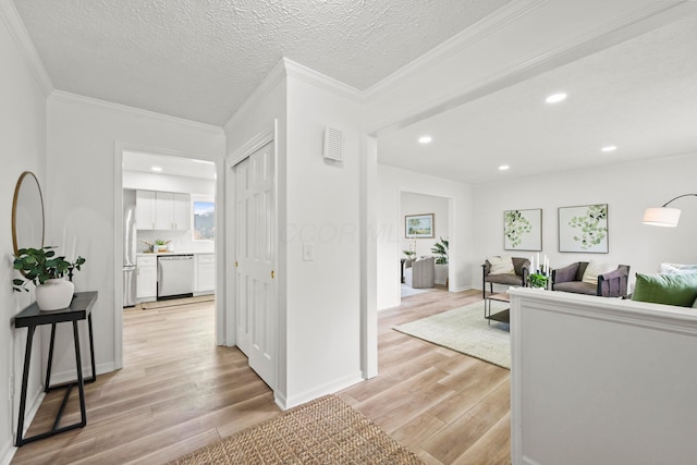 hall with light wood-style flooring, ornamental molding, and a textured ceiling