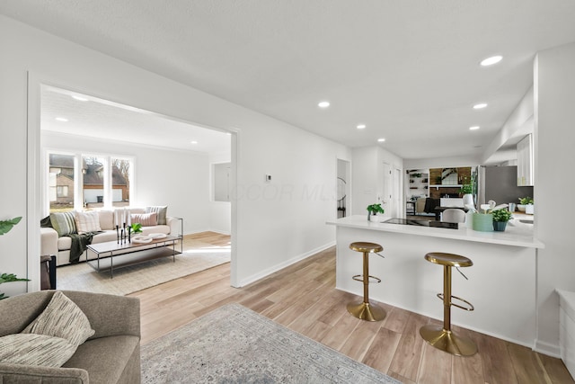 kitchen featuring light countertops, light wood-style floors, white cabinets, a peninsula, and a kitchen breakfast bar