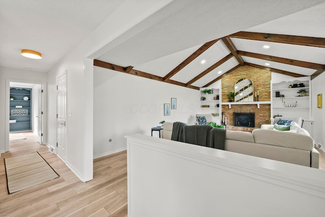 living area with a brick fireplace, baseboards, built in features, lofted ceiling with beams, and light wood-style floors