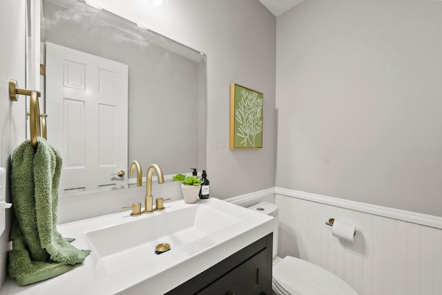 bathroom featuring toilet, wainscoting, and vanity