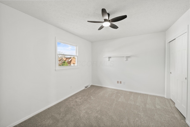 unfurnished bedroom featuring a textured ceiling, carpet floors, a ceiling fan, baseboards, and a closet