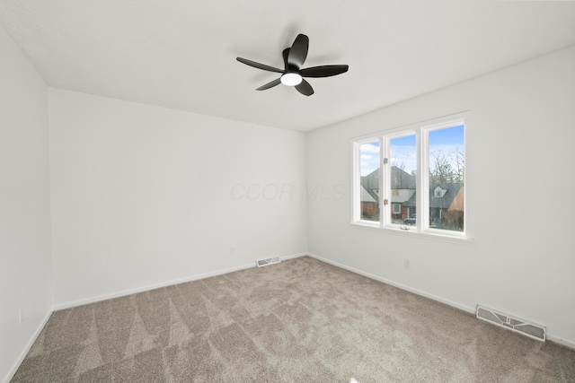 carpeted spare room with ceiling fan, visible vents, and baseboards