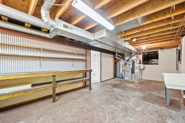 unfinished below grade area featuring concrete block wall, visible vents, and heating unit