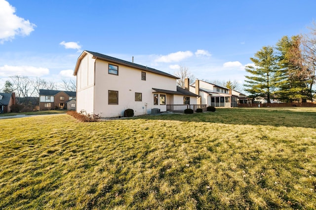 rear view of house with stucco siding, fence, cooling unit, and a yard