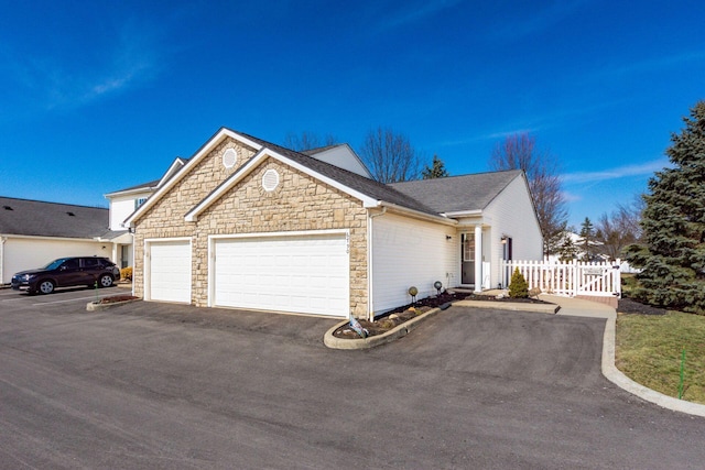 ranch-style home with aphalt driveway, a gate, fence, and a garage