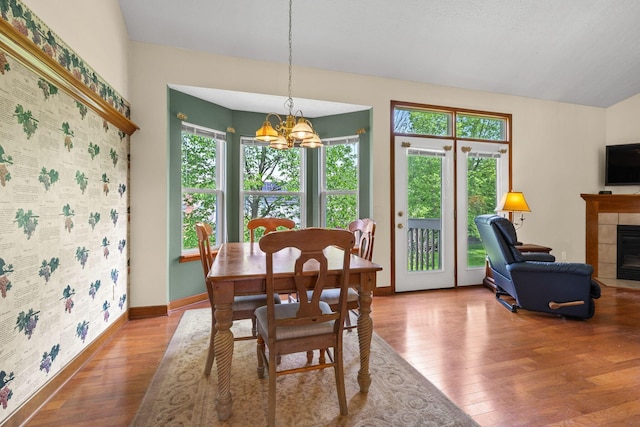 6266 Misty Cove Ln, Columbus, OH 43231 - dining space featuring a chandelier, wood finished floors, a tiled fireplace, and healthy amount of natural light