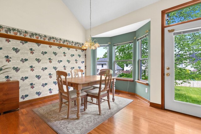 6266 Misty Cove Ln, Columbus, OH 43231 - dining room featuring baseboards, a chandelier, wallpapered walls, light wood-style flooring, and vaulted ceiling