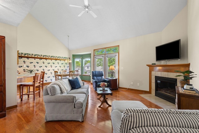 6266 Misty Cove Ln, Columbus, OH 43231 - living room with a tile fireplace, wood finished floors, ceiling fan, baseboards, and high vaulted ceiling
